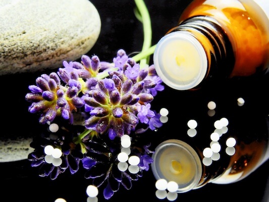 Homeopathic globules and purple flower on a mirror